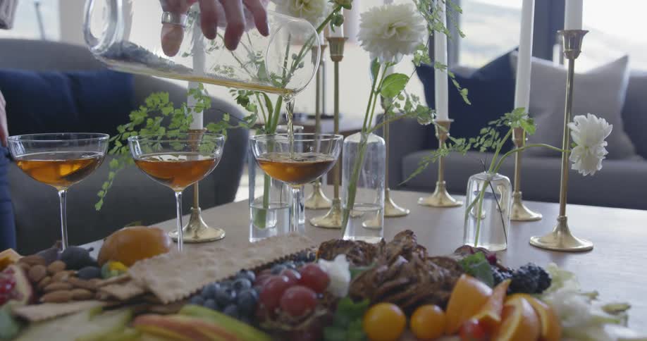 A person is pouring drinks into glasses on the table