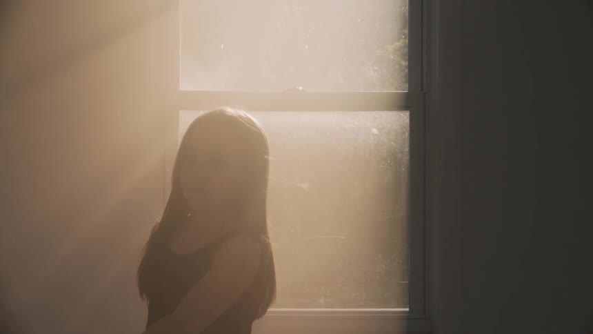 Girl dances in front of a sunny window
