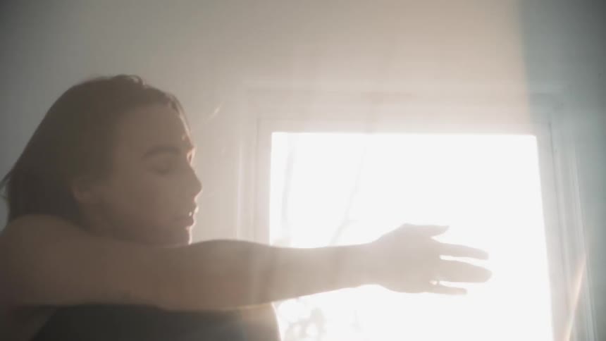 The woman dances around in front of the window