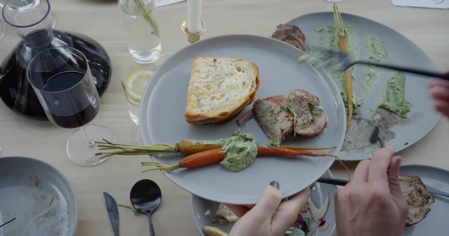 Person scoops green sauce on top of carrots on a plate