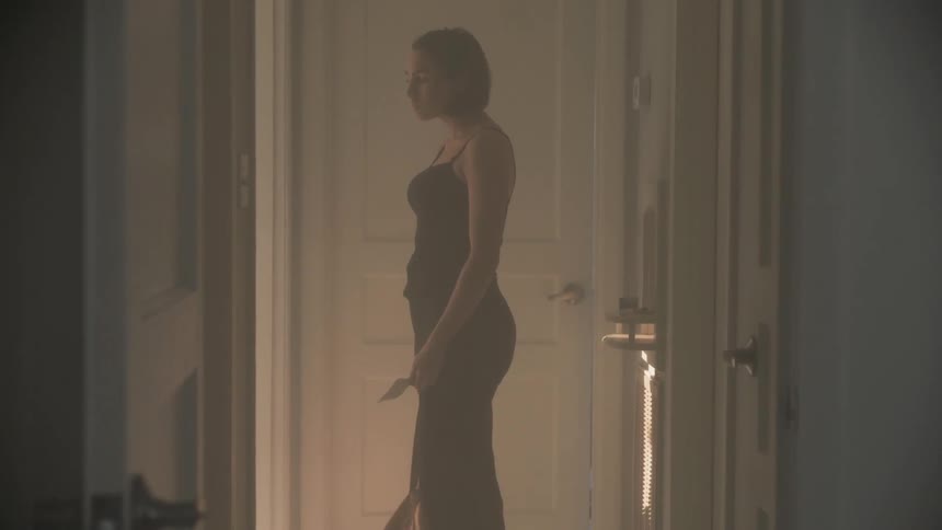 Woman in a black dress stands near an open doorway