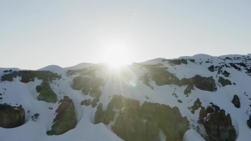 Sun rises over snowy rocky mountains
