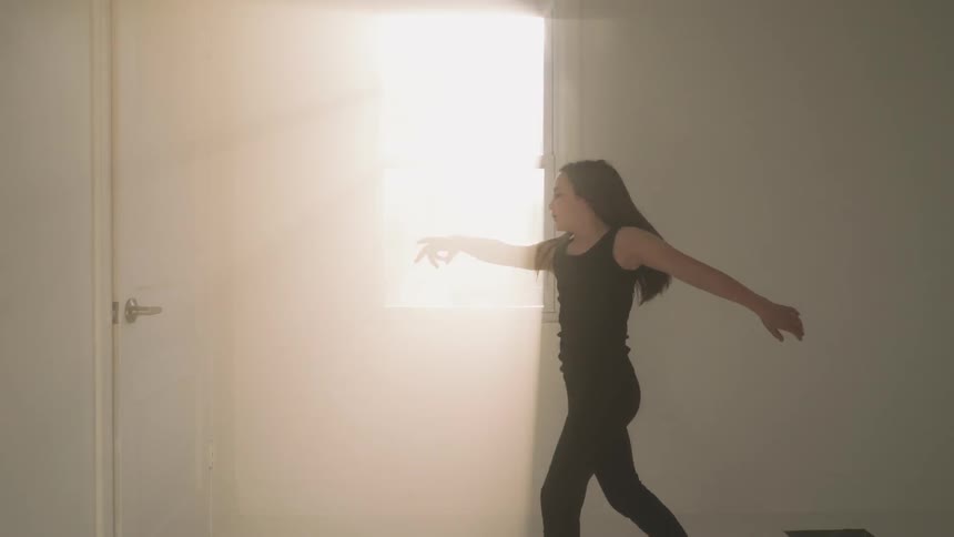 A woman is spinning around as she dances in the room