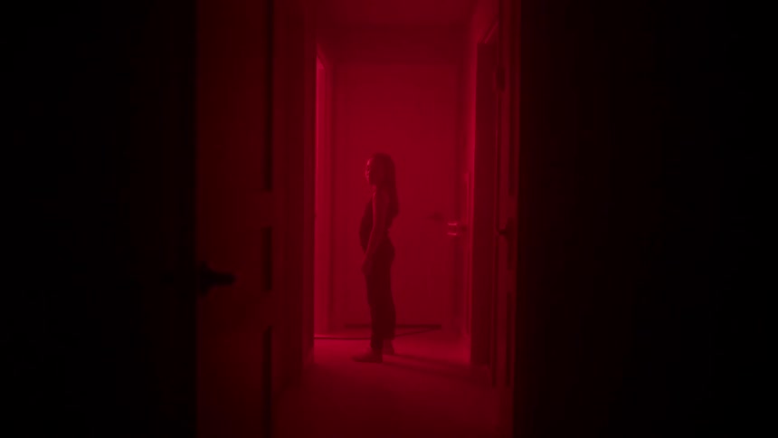 Girl stands in a dark hallway with flashing lights