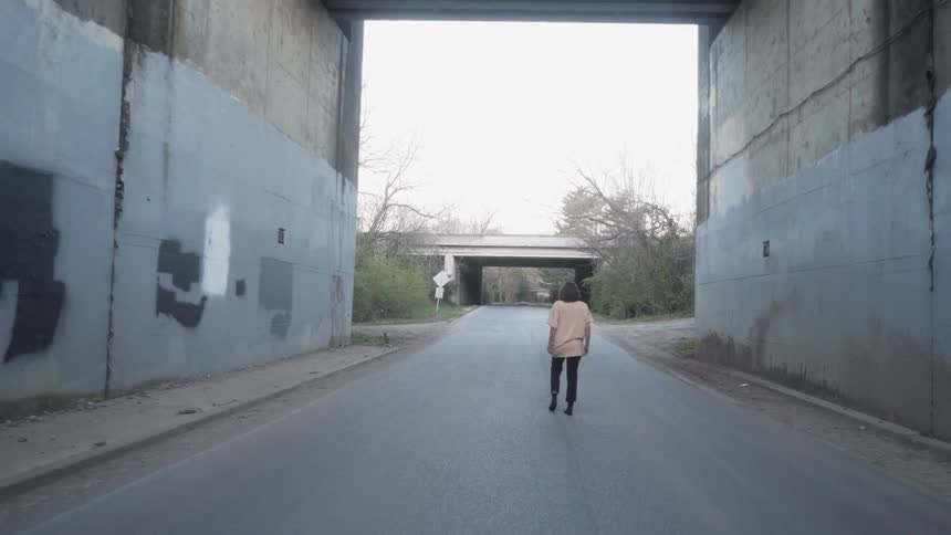 A woman dances under an underpass in her socks