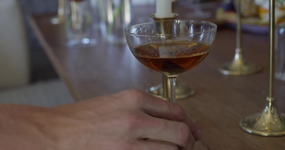 A man picks up a glass from the table