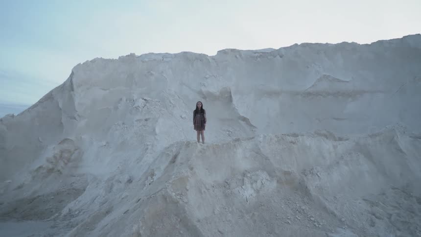 Woman stands on a large dirt pile