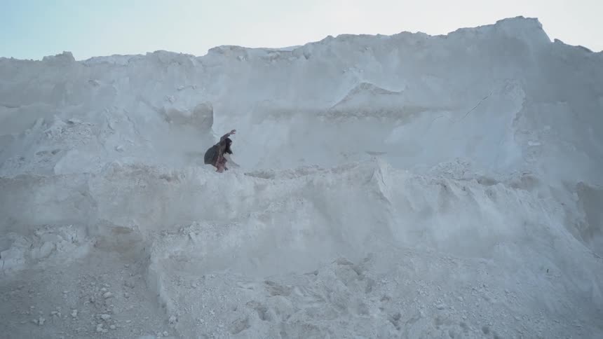 A person is jumping over the rocks on the side of the mountain