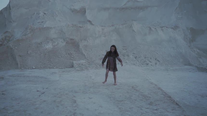 Girl dances outside next to a large rock formation
