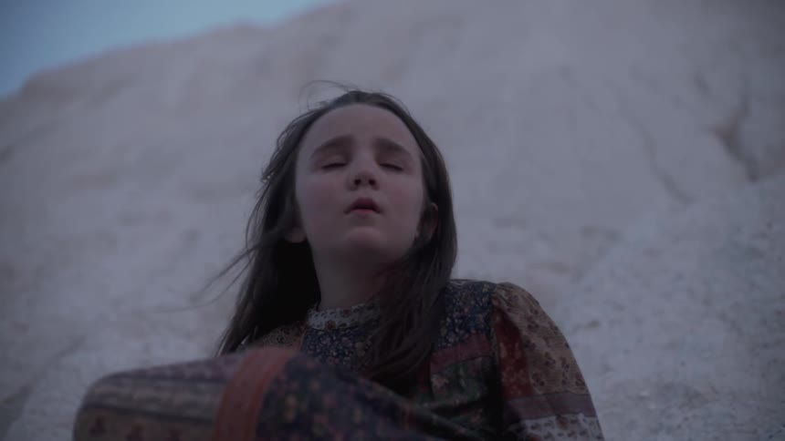 Sad girl sits outside on a sand pile