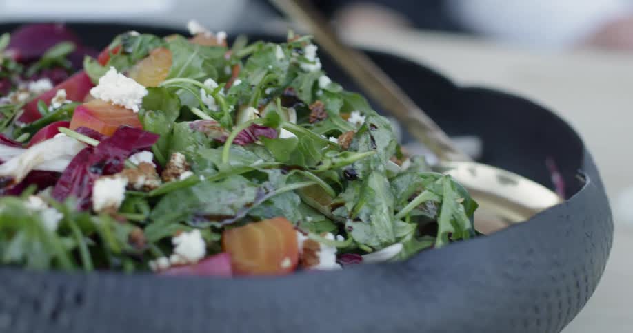 Glass of wine sits next to a vegetable salad