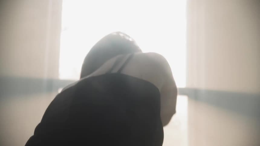 A woman is stretching and turning as she dances inside in daylight