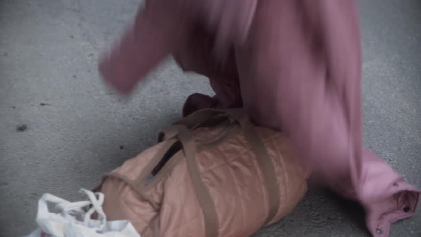 Person takes their coat and shoes off and leaves them next to some bags