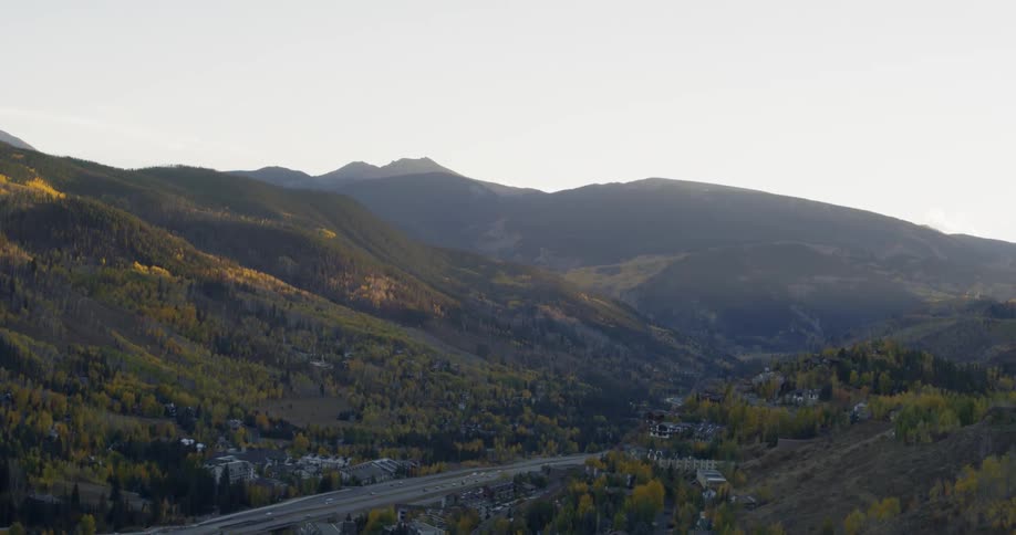 The mountain range is covered with green with some homes near the road