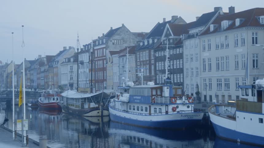 The canal has many boats docked by the buildings