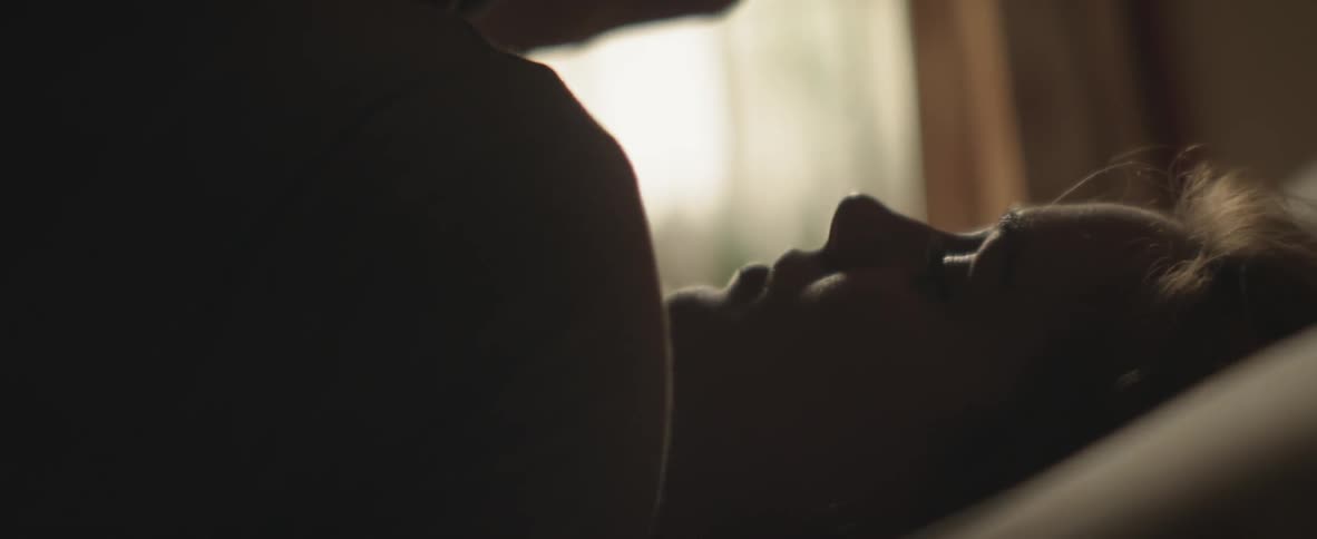 Woman caresses a man's hair as they lay in bed