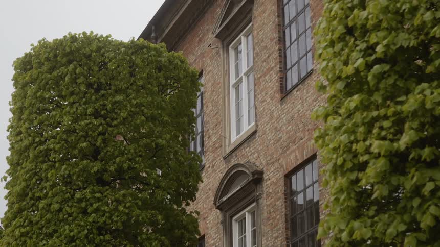 Trimmed hedges in front of a brick house