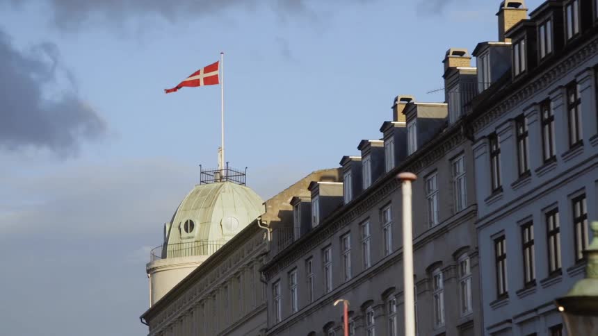 A flag is waving in the breeze atop a domed building during the day