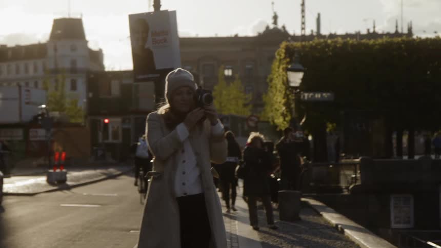 Woman takes a picture on a crowded city street
