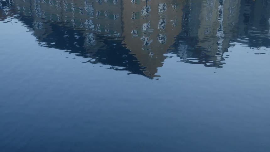 The water is reflecting the building on a sunny day
