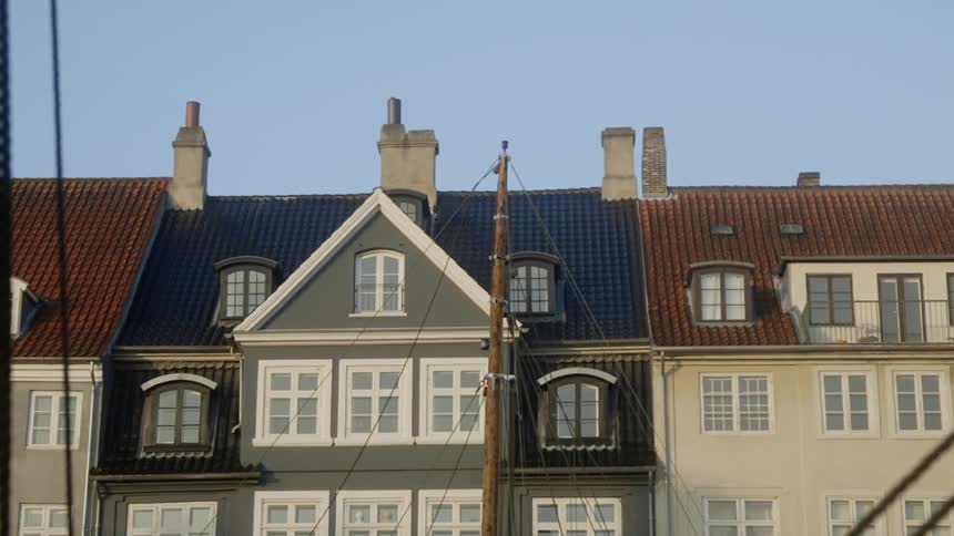 The masts of docked ships stand in front of row houses