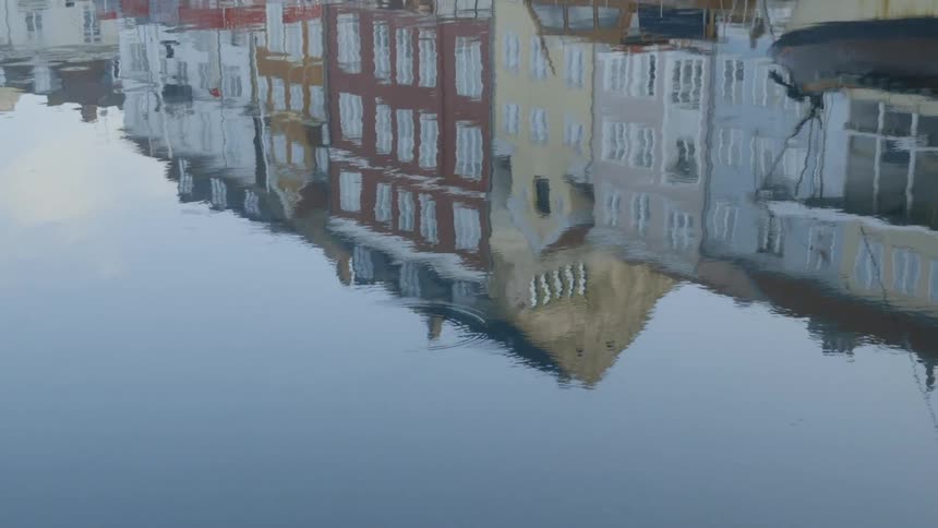 Buildings are reflected in rippling water