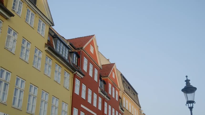 The sun is shining high above these neighborhood buildings