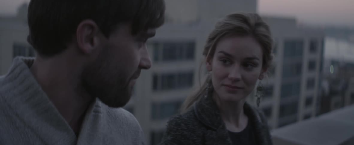 Man and woman talking on a rooftop after sunset