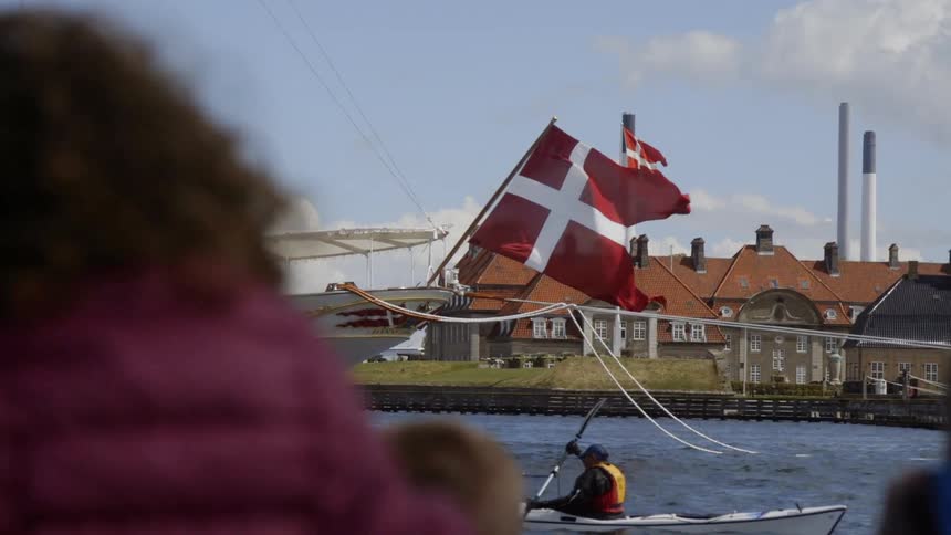 A person is rowing a canoe past a large boat