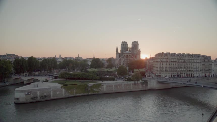 The sun sets over a river and city buildings