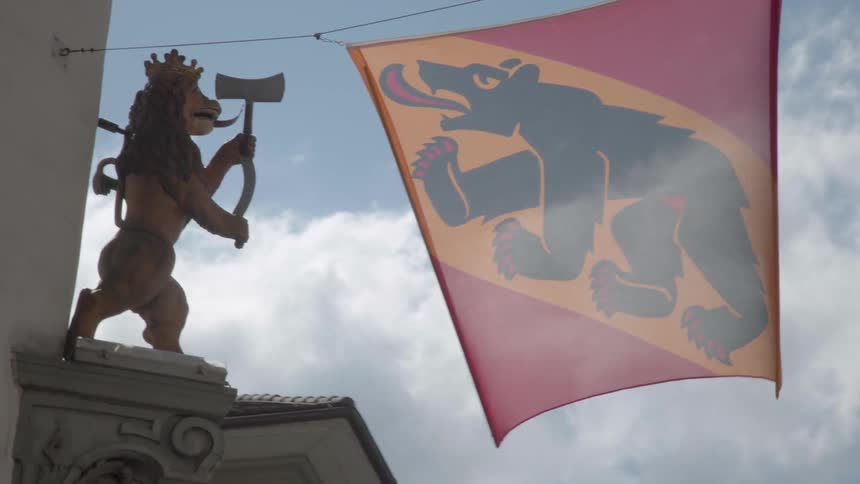 A banner is hung near a statue in a city