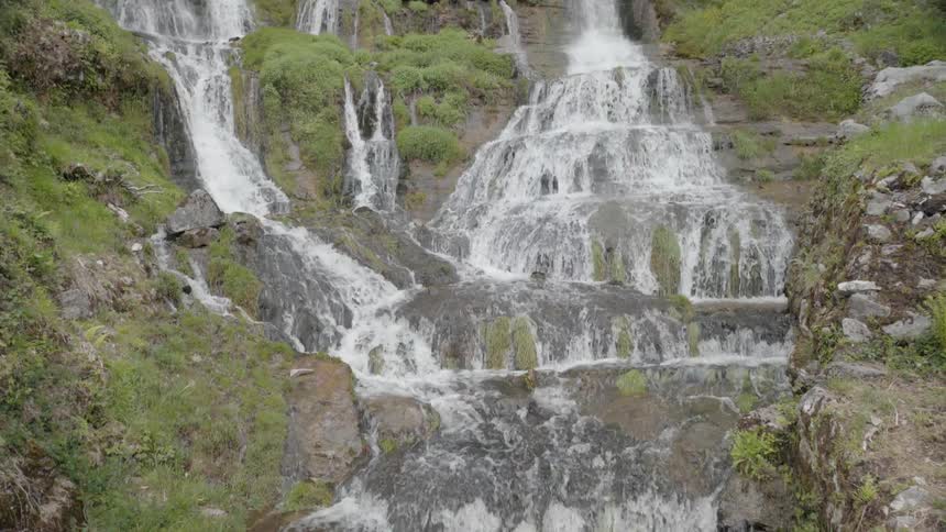 Water flows down a mountain in front of a building