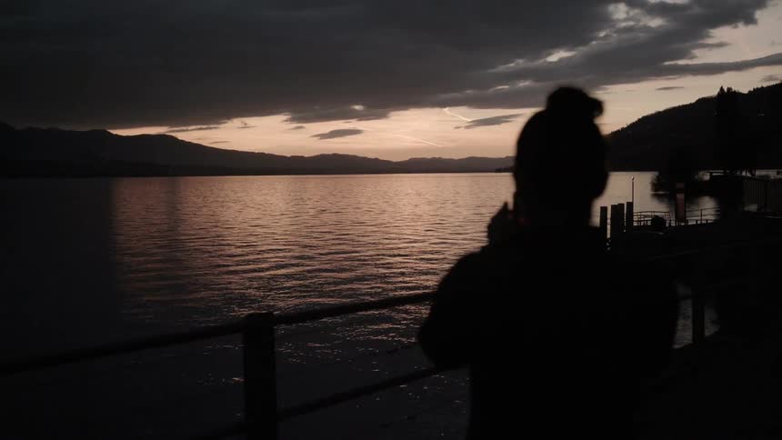 Woman looks out across the water at sunset