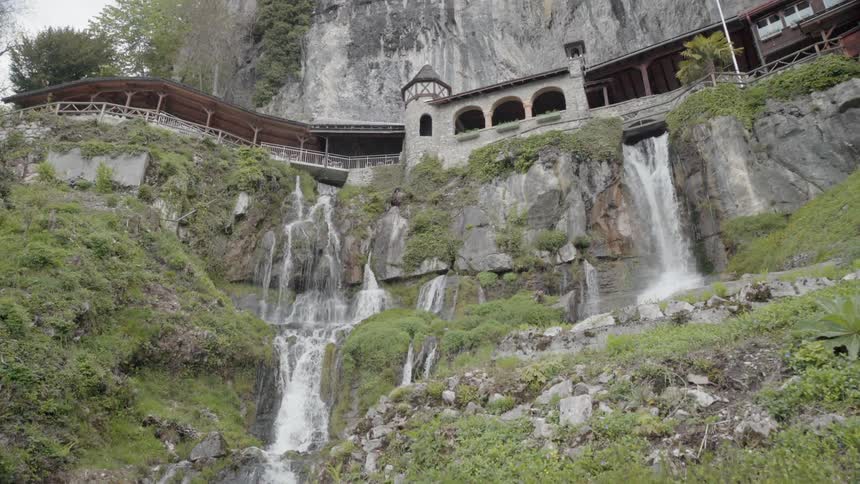 A building sits perched on a cliff with waterfalls