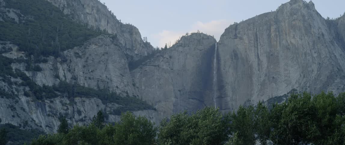 The tall mountain has trees below