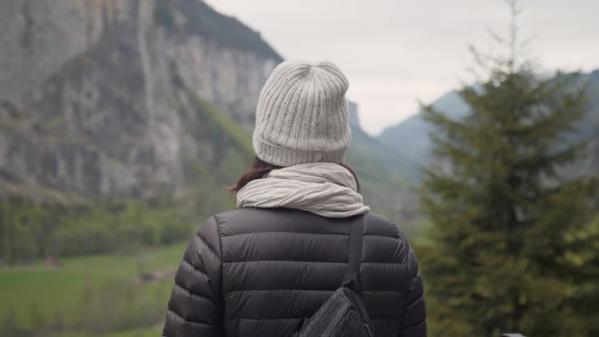 The woman stands on the hill looking at the mountain range