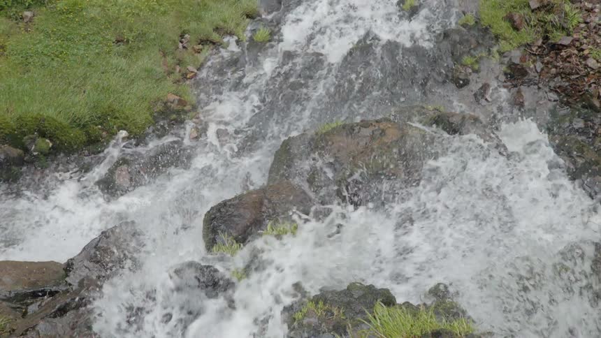 A stream is cascading down rocks as it flows on a sunny day