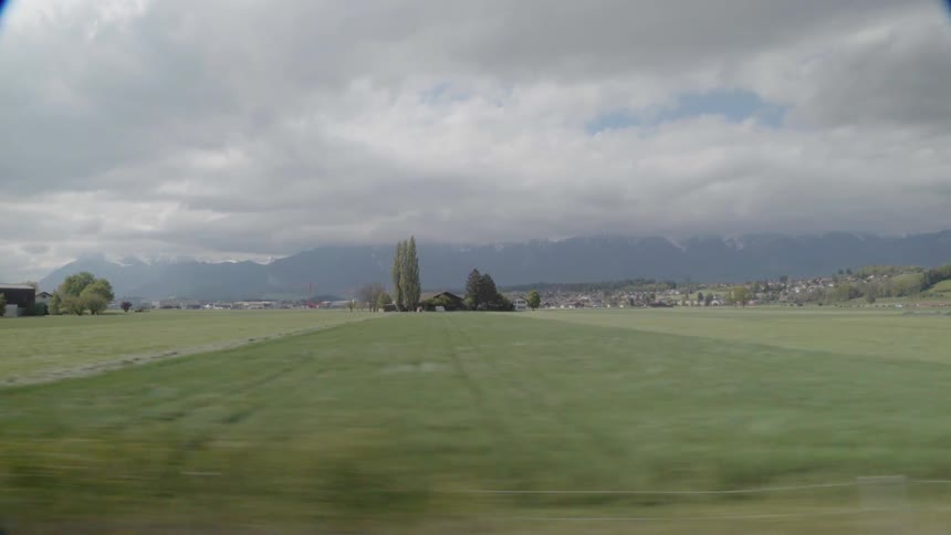 Traveling past farm fields and houses on a cloudy day