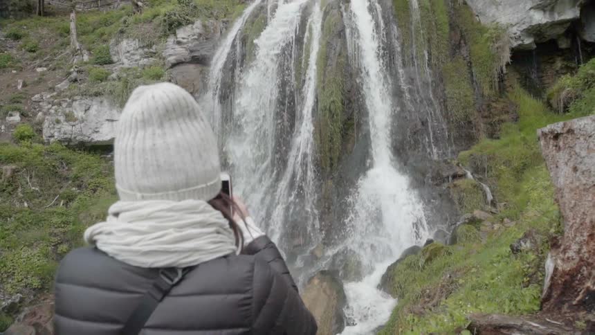 A woman photographs a waterfall