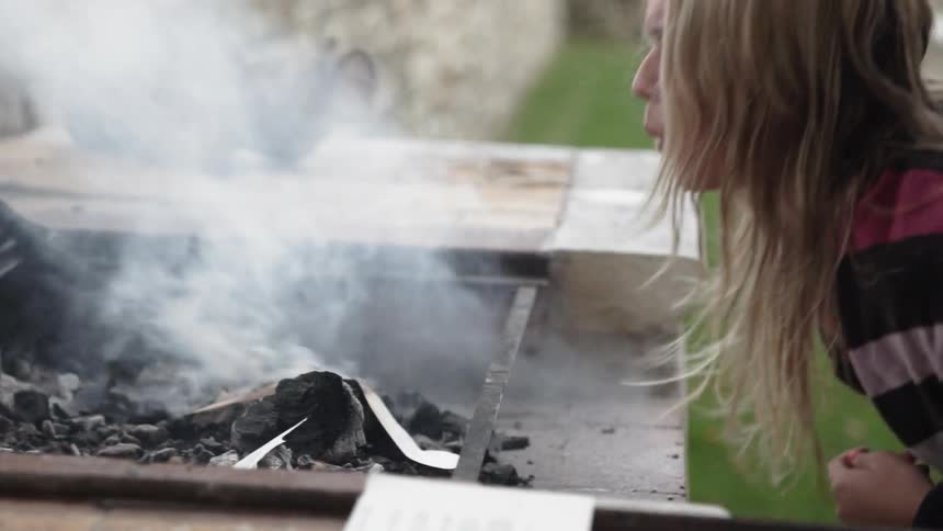 A woman is starting a fire with pages of a book