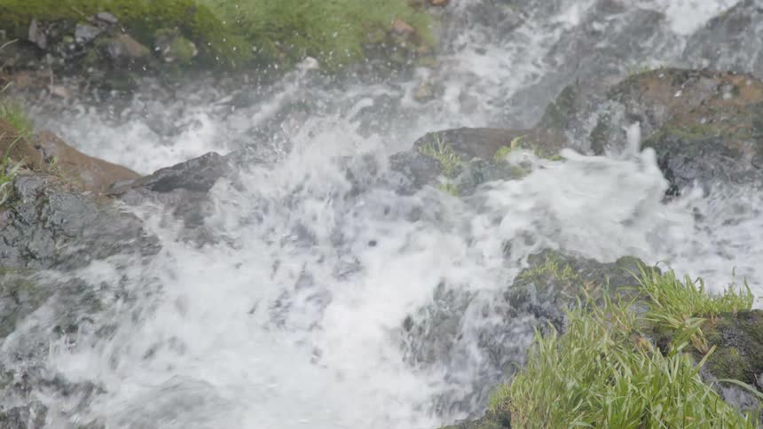 The waterfall rages down the side of the rocks