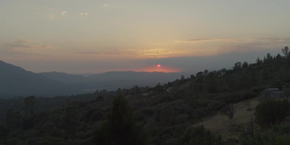 Sun sets over hills and trees
