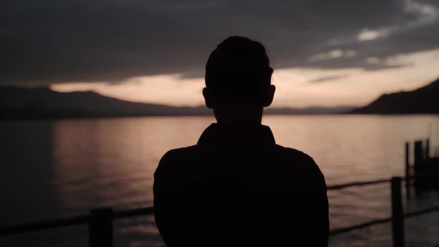 Person looks out across the water at sunset