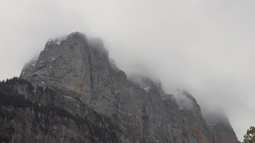 Mist floats over a mountain under a cloudy sky