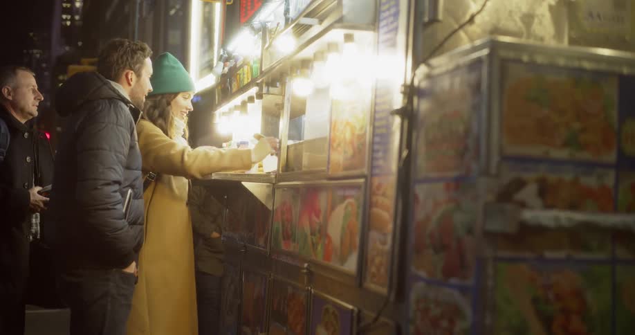 A man and woman order food at a food cart