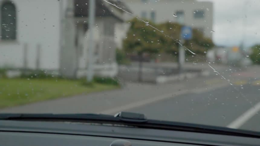Car drives on a town street in the rain