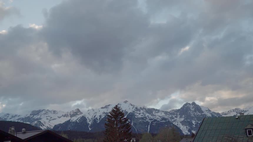 Clouds hang above the snow covered mountain