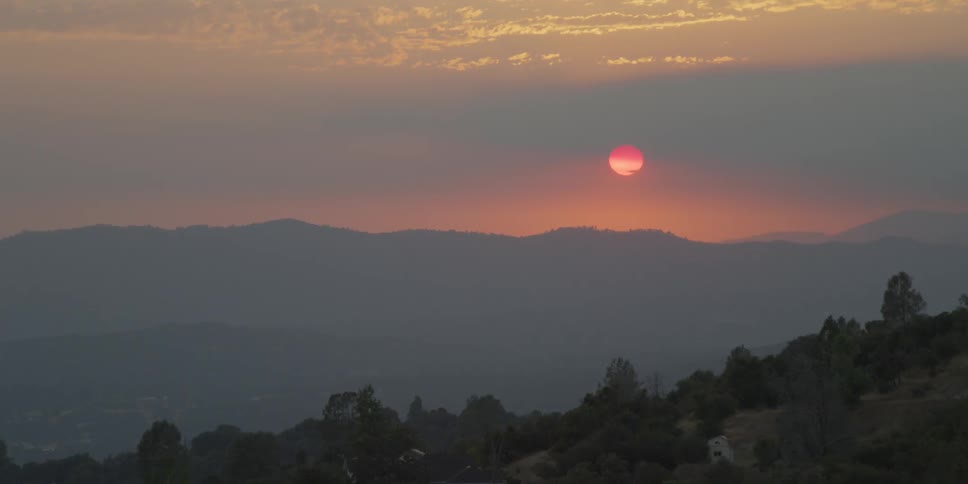 Sun sets over hills and trees