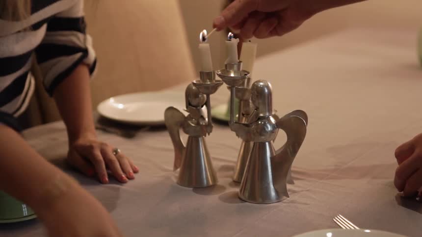 People are setting a table and lighting candles