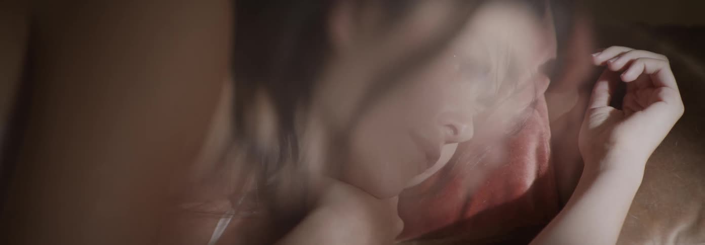 Sunlight comes through the curtain and shines on a sleeping woman